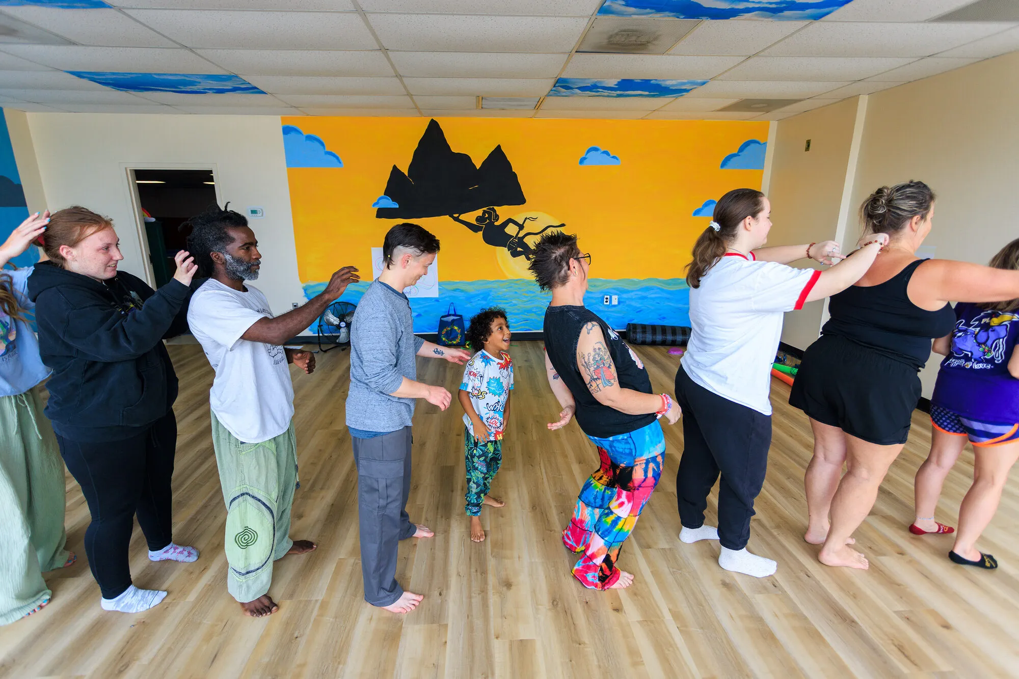A line of people of different ages standing together with hands on each other's shoulders