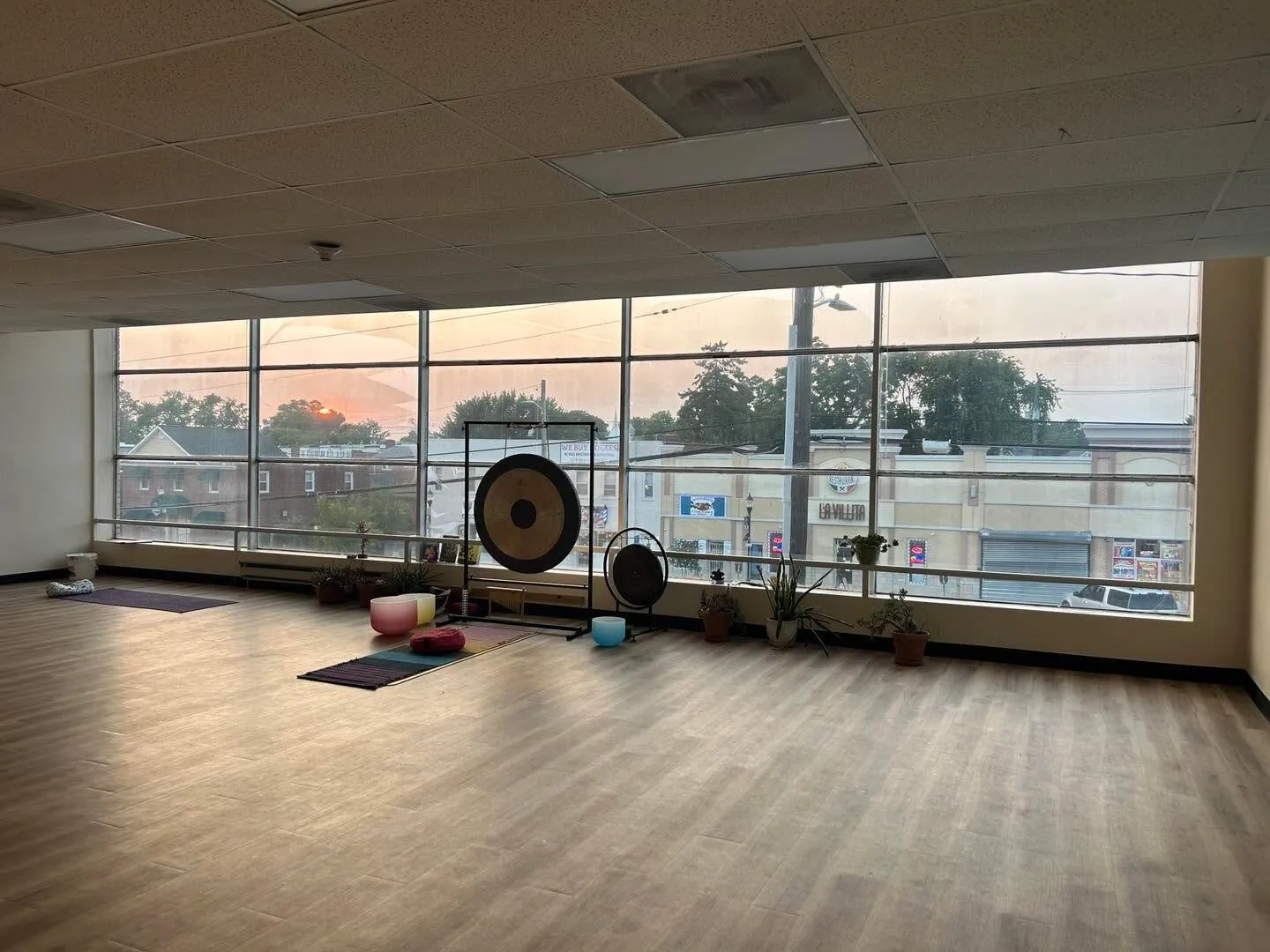 The club studio at sunset: wooden floor, a large gong, and windows along the far wall